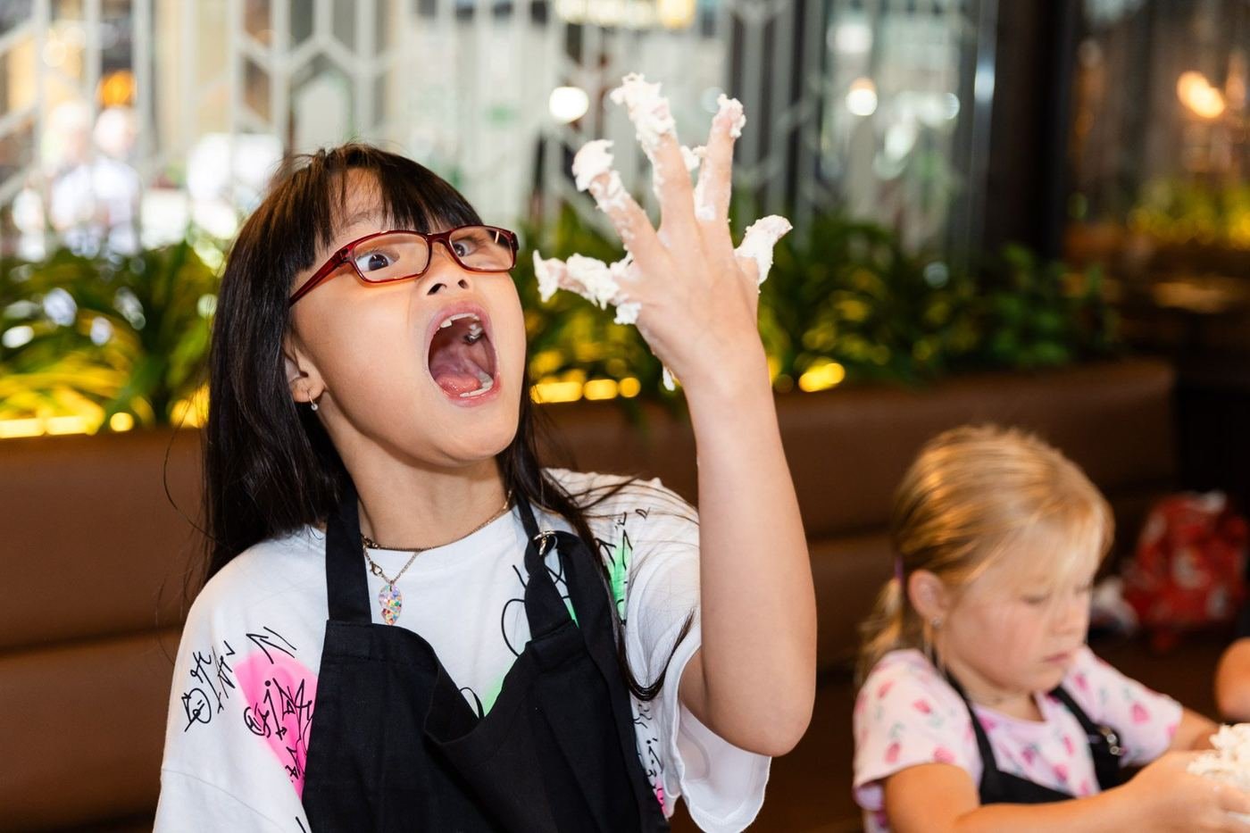 A girl laughing with dough on her fingers at a Belliney's pizza class
