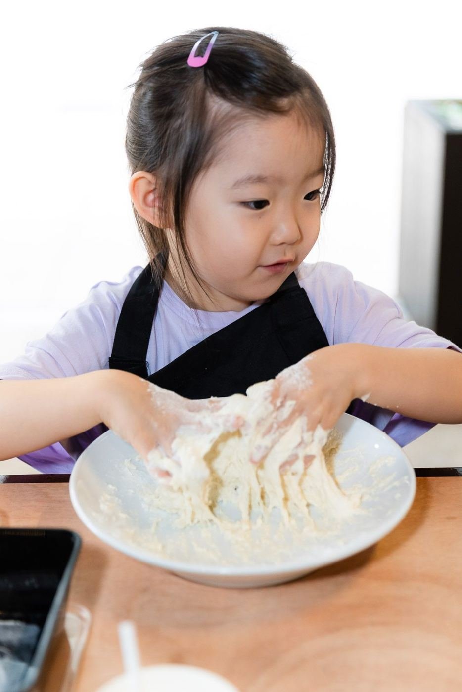 Child kneading pizza dough in a bowl