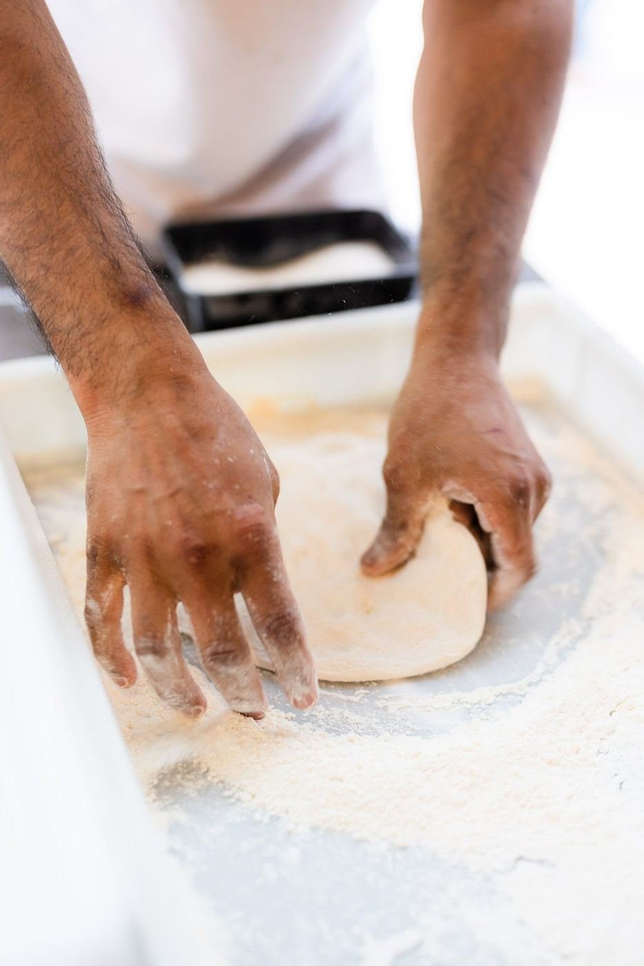 Hands pressing out a ball of pizza dough