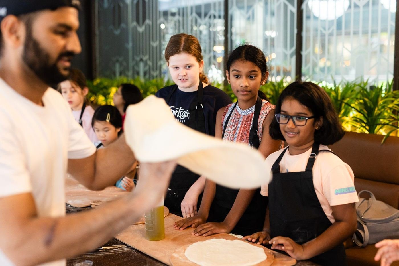 A pizza chef stretching dough in front of a group