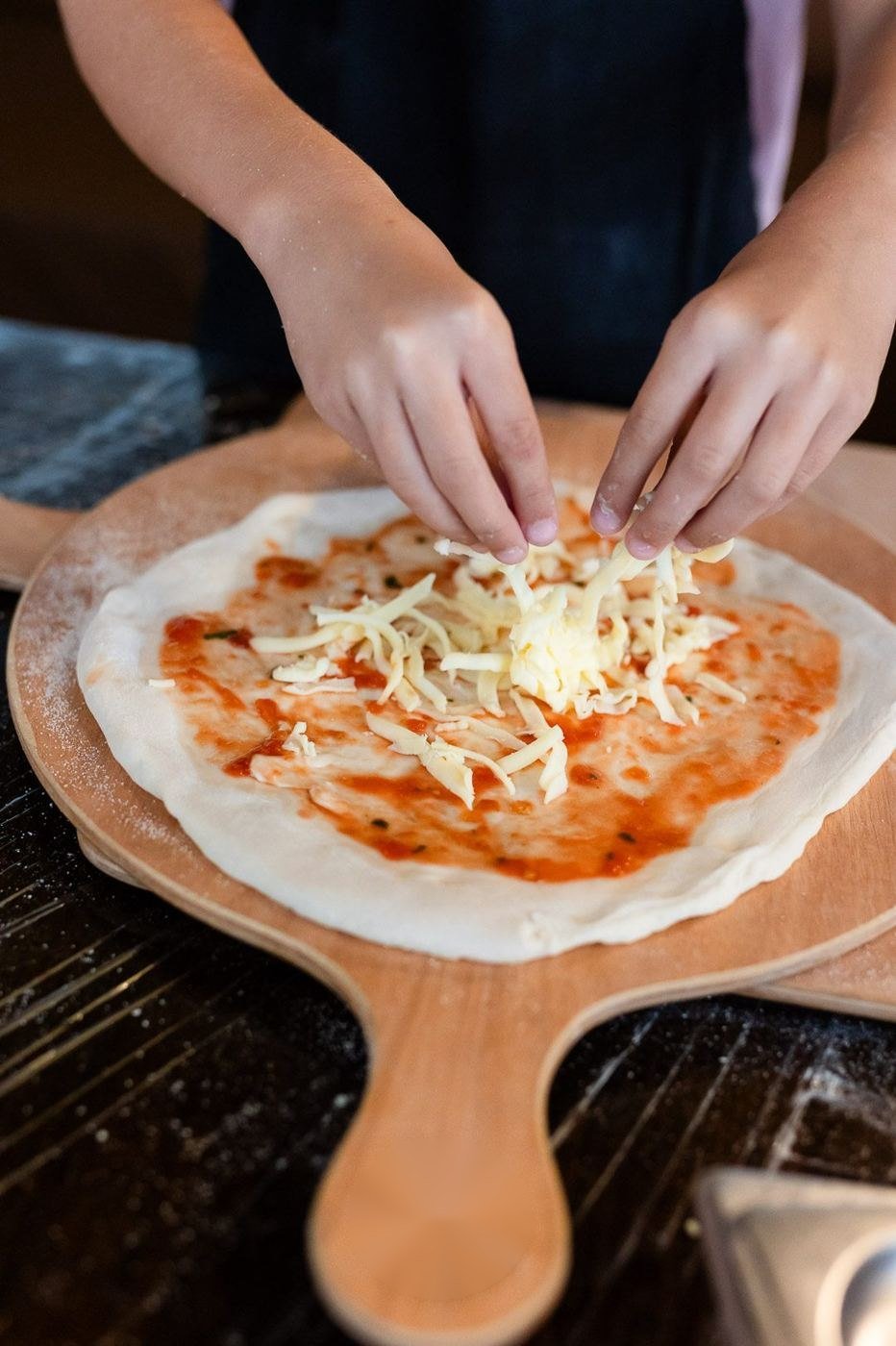 Cheese being scattered on a pizza base